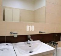 Badezimmer in einer 4-Zimmer-Wohnung mit Waschbecken, Spiegel und Waschmaschine.