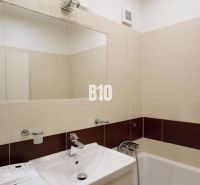 Badezimmer mit Dusche und Waschbecken in einer 4-Zimmer-Wohnung, cremefarbene Fliesen.