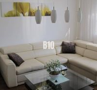 Elegantes Wohnzimmer in einer 4-Zimmer-Wohnung mit cremefarbenem Sofa und Boden in Holzoptik.