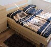 Schlafzimmer mit gemusterten Bettbezügen, Kommode und Boden mit Holzdekor in einer 4-Zimmer-Wohnung.
