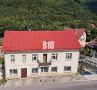 Ein Gebäude in Belej mit rotem Dach, umgeben von Grün und einer Straße im Vordergrund.