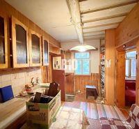 Küche eines Einfamilienhauses mit Holzschränken und gefliester Wand.