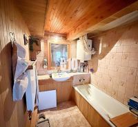 Ein Badezimmer in einem Einfamilienhaus mit Holzverkleidung und einer Badewanne.