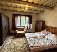 Ein Schlafzimmer in einem Einfamilienhaus mit Teppich, Sofa und Bett unter einer Holzdecke.