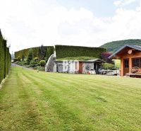 Ein gepflegter Rasen bei der Villa in Súľov-Hradná mit einem Holzhaus und einer Hecke.