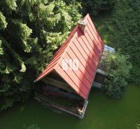 Eine Hütte in Kunerad mit einem schrägen Dach, umgeben von dichtem Baumbestand.