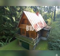 Eine Hütte in Kunerad, umgeben von Wald, mit Holzelementen und einem Steinfundament.