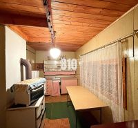 Eine Küche in einer Hütte mit Holzdecke und antikem Herd, ergänzt durch einen Vorhang.