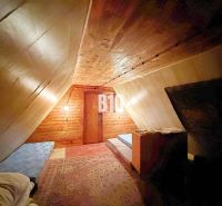Das Dachgeschoss der Hütte mit schräger Decke, Betten und Boden in Holzoptik.