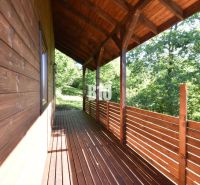 Die Holzterrasse der Hütte in Bytča, umgeben von Grün und Waldlandschaft.