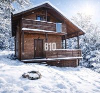 Eine verschneite Holzhütte in Bytča, umgeben von Wäldern.
