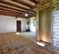 Interieur einer Hütte mit Holzbalken, Holzboden und einem Ofen zum Heizen.