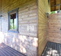 Eine Holzhütte mit Terrasse in Bytča, umgeben von Natur und Sonnenlicht.