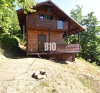 Eine Holzhütte in der Natur bei Bytča, umgeben von Bäumen und einer Feuerstelle.