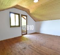 Dachbodenräume der Hütte mit Holzboden und -decke, Fenster und Tür zur Terrasse.