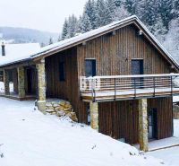 Eine verschneite Hütte in Horná Mariková, umgeben von Wald und schöner Winterlandschaft.