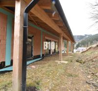 Ein im Bau befindliches Einfamilienhaus mit einem hölzernen Unterstand, ebenem Gelände und umliegender Landschaft.