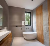 Ein Badezimmer in einer Hütte mit freistehender Badewanne, Holzelementen und einem großen Fenster.