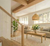 Das Innere der Hütte mit einem Sofa, einem Tisch, einer Pflanze und einem Boden mit Holzdekor.