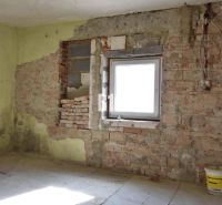 Ein Zimmer in einem Einfamilienhaus mit Ziegelwänden und einem Eimer auf dem Boden.