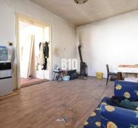 Ein Zimmer in einem Einfamilienhaus mit einem Holzboden, einem Ofen und Möbeln mit Blumenstoff.