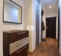 Flur mit Spiegel, Kommode und Boden mit Holzdekor in einer 3-Zimmer-Wohnung.