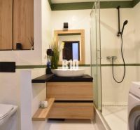 Badezimmer in einer 3-Zimmer-Wohnung mit Holzdekor und Duschkabine.