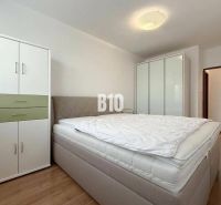 Helles Zimmer in einer Ferienwohnung mit Bett, Kleiderschränken und Holzboden.