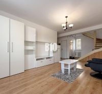 Wohnzimmer in einer Ferienwohnung mit weißen Möbeln und einem Boden in Holzoptik.