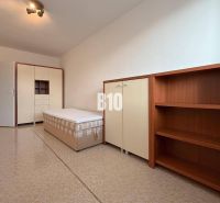 Helles Zimmer in einer Ferienwohnung mit Bett, Schrank und Regalsystem.