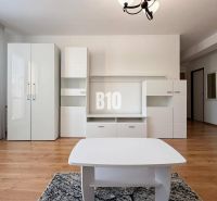 Innenraum einer Ferienwohnung mit weißen Möbeln und Boden in Holzoptik.
