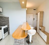 Küche mit Bartresen und gefliester Wand in einer Einzimmerwohnung.