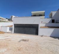 Eine Villa in Žaborić mit weißer Fassade und eingebauter Garage am Hang.
