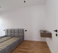 Schlafzimmer in einer Villa mit einem Bett und einem Boden in Holzoptik, schneeweiße Wände.
