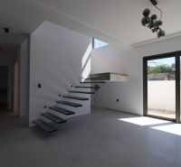 Eine Treppe mit offenen Stufen im Inneren der Villa und einem großen Fenster.