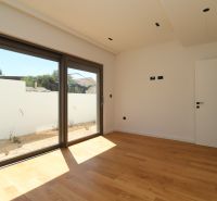 Zimmer in der Villa mit Holzboden und großem Fenster zur Terrasse.