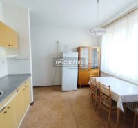 Küche in einer Einzimmerwohnung mit Esstisch und Boden in Holzoptik.