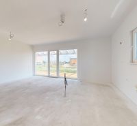 Das Innere eines Einfamilienhauses mit weißen Wänden und großen Fenstern zum Garten.