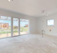 Ein geräumiges Zimmer mit großen Fenstern und Betonboden in einem Einfamilienhaus.