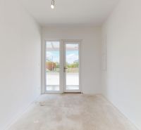 Innenraum eines Einfamilienhauses mit weißen Wänden und Glastüren zur Terrasse.