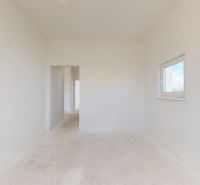 Ein geräumiges Zimmer in einem Einfamilienhaus mit weißen Wänden und einem Fenster.