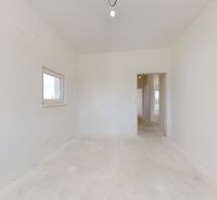 Ein heller Raum in einem Einfamilienhaus mit einem Fenster und einer einfachen Leuchte.