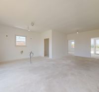 Ein geräumiges Zimmer in einem Einfamilienhaus mit Betonboden und einem großen Fenster.