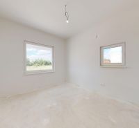 Ein leerer Raum mit weißen Wänden und großen Fenstern in einem Einfamilienhaus.