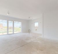 Ein geräumiges Zimmer in einem Einfamilienhaus mit großen Fenstern ohne Bodenbelag mit Holzdekor.