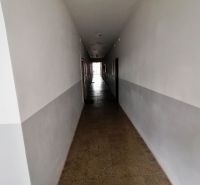 Ein langer Flur mit weißen Wänden und Fliesenboden in einer Einzimmerwohnung.