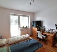 Schlafbereich in einer Einzimmerwohnung mit Holzboden und Schreibtisch.