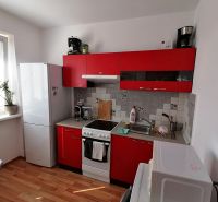 Küche mit roten Schränken und Holzdekorboden in einer Einzimmerwohnung.