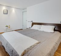 Schlafzimmer in einer 3-Zimmer-Wohnung mit einem bequemen Bett und einem Boden in Holzoptik.