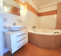 Badezimmer mit einer Eckbadewanne, einem Waschbecken und einer Waschmaschine in einer 3-Zimmer-Wohnung.